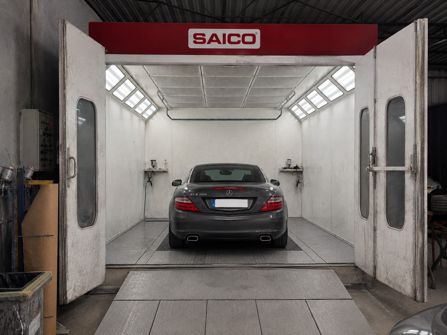 Câmara de pintura da oficina, com um carro lá dentro e as portas abertas